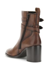 Hnědé kožené kotníkové boty s vysokým blokovým podpatkem, bočním zipem a dvojitým páskem kolem kotníku. Texturovaný povrch a zaoblená špička.