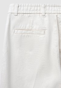 Weiße Baumwollhosen mit einer glatten Textur, ausgestattet mit einem normalen Bund und einer Gesäßtasche mit einer einzelnen horizontalen Naht.