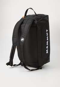 Black backpack with padded mesh straps, a durable exterior, reflective accents, and white logo detailing. Features a top handle for carrying.