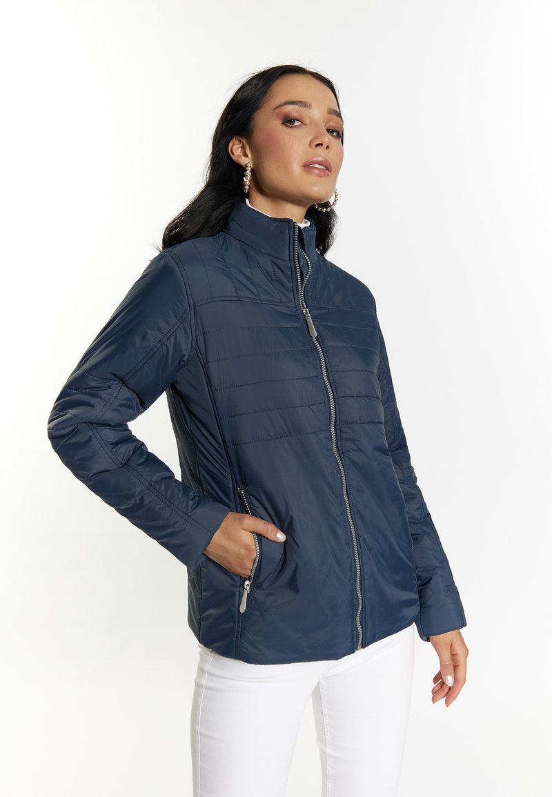 Giacca blu navy con zip, colletto alto e texture trapuntata. Presenta tasche laterali e un design elegante e leggero.