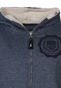 Felpa con zip blu scuro mélange, foderata in pile, con zip frontale e un'etichetta circolare blu navy sul petto.