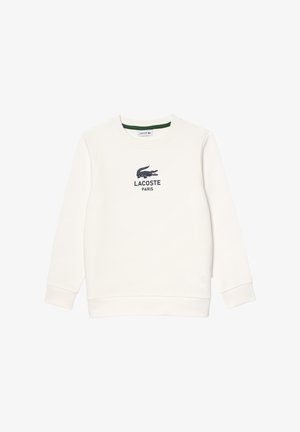 Biała bluza wykonana z bawełny, z okrągłym dekoltem. Posiada granatowe logo Lacoste oraz napis "PARIS" na klatce piersiowej. Klasyczny krój.