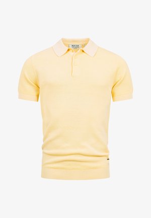 Bladożółta koszulka polo z krótkim rękawem z teksturowanej tkaniny, prążkowanymi mankietami i dołem, listwą z trzema guzikami oraz miękkim, ostrym kołnierzem.