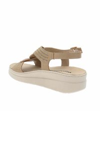 Sandali platform beige con cinturino testurizzato e accenti di strass, caratterizzati da un retro aperto e un design a ritaglio per la traspirazione.