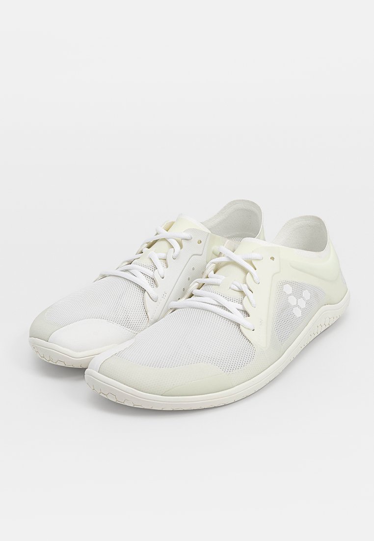 Zapatillas de malla blancas con una puntera texturizada y un sutil detalle en el costado. Los cordones son blancos; la suela es resistente y ligeramente curvada.