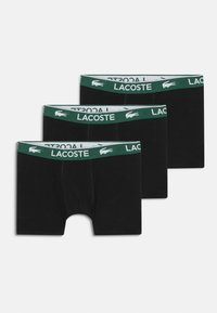 Sorte boxer shorts med en grøn og hvid Lacoste elastik, der har en glat tekstur og en midt-lår længde. Sælges i en pakke med tre.