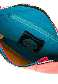 Borsetta con cerniera in pelle rosa brillante. L'interno presenta una fodera blu, un fondo giallo e una piccola tasca con cerniera. L'etichetta riporta "Made in Italy."