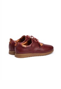 Zapatos de cuero burdeos con puntera redonda, cordones en tono a juego y suela de goma marrón texturizada. La parte trasera presenta un pequeño parche con el logotipo y un lazo.