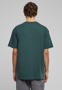 Mørkegrøn kortærmet t-shirt med en afslappet pasform, rund halsudskæring og glat bomuldsstruktur. Ingen synlige mønstre eller detaljer.