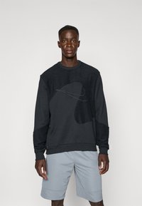 Dark gray sweatshirt with textured accents and abstract design, paired with light gray athletic shorts. Smooth fabric with a crew neck.