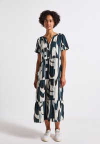 Abito maxi stampato in tonalità di teal, crema e nero, con maniche corte, scollatura a V e design a volant con vestibilità ampia.