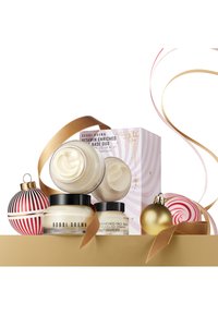 Bobbi Brown Vitamin Enriched Base Duo som består av to kremkrukker, en stor og en liten, med svarte lokk. En gull satengbånd og festlige ornamenter inkludert.