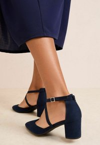 Tumesinised kontsakingad seemisnahast tekstuuriga, pahmril rihm hõbedase pandlaga, ümmarguse ninaga ja plokkkontsa disainiga.