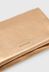 Portafoglio in pelle oro metallizzato con finitura testurizzata, caratterizzato dalla marcatura a caldo "ALLSAINTS", bordi lisci e design sottile.