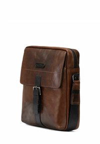 Brązowa skórzana torba listonoszka z klapą, czarnym paskiem i metalowym zapięciem. Charakteryzuje się gładką teksturą i minimalistycznym designem. Zamek błyskawiczny.