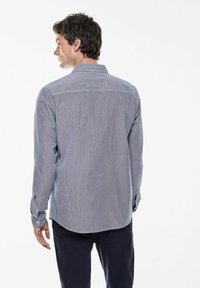 Modrá a bílá pruhovaná košile s dlouhým rukávem a límečkem na knoflíky, se rovný lem a nastavitelnými manžetami, vyrobená z lehkého materiálu.