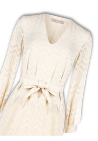 Cremefarbenes Kleid mit V-Ausschnitt, langen Ärmeln, Bindegürtel und einem gezackten Strukturmuster. Hergestellt aus leichtem Stoff.