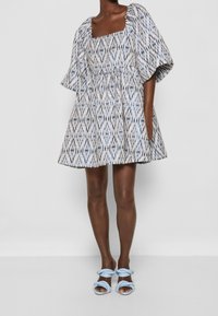 Mönstrad klänning med fyrkantig halsringning, korta puffärmar och åtsittande midja. Tillverkad av lätt tyg i vita, blå och grå nyanser.