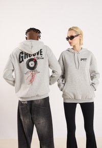 Gray hoodies feature printed designs: one with "GROOVE in Bloom" and a vinyl record graphic on the back, another with a smaller logo on the front.