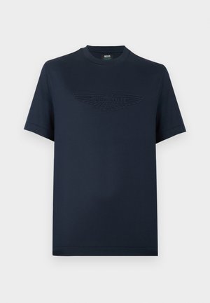 Μπλε βαμβακερό T-shirt με κοντά μανίκια, με ανάγλυφο λογότυπο φτερών Aston Martin στο μπροστινό μέρος. Κλασικός στρογγυλός λαιμός, άνετη εφαρμογή.