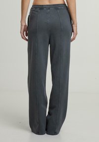 Grijze, wijde broek met een trekkoord in de taille, zichtbare naaddetails en zijzakken. Zachte textuur, casual pasvorm en geen zichtbare logo's.