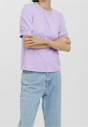 T-shirt en coton lavande clair avec des manches bouffantes courtes, un col rond et une coupe décontractée. Porté avec un jean en denim bleu clair.