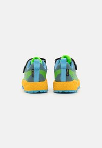 Baskets de sport grises et bleues avec des semelles jaunes et des accents verts, dotées d'une semelle en caoutchouc texturé et de fermetures à sangle réglables.
