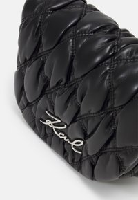 Black quilted leather handbag featuring a puffy design, smooth texture, and silver logo accent. Shape is soft and rounded.