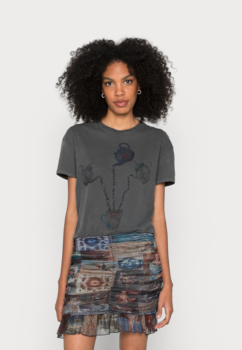 Szara bawełniana koszulka z grafiką imbryka i napisem, połączona z warstwową, wielowarstwową spódnicą z krótkim fasonem, zdobioną historycznymi wzorami.