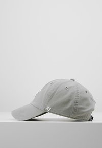 Gray baseball cap made of cotton, featuring a curved brim, embroidered logo on the front, and a fabric tag on the side.