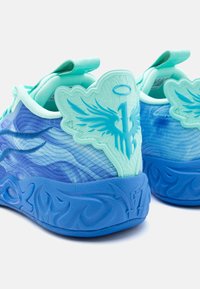 Sportssko med et bølget blåt og aqua design, som har teksturerede detaljer, formede vingeformer og en skulptureret gummisål.