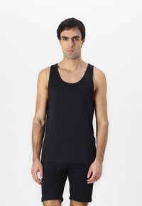 Top sin mangas de algodón negro con escote redondeado, combinado con pantalones cortos negros a juego. La tela parece suave y ligera.