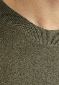 Olivenfarbener Strickpullover mit ribbelndem Rundhalsausschnitt und glatter Textur, mit sichtbaren Nähten und einem leicht melierten Muster.