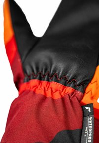 Wasserdichte Handschuhe mit einer schwarzen Lederhandfläche, einem rot-orangefarbenen Stoffkörper, elastischem Bund und einem Etikett mit der Aufschrift "WASSERDICHT WEICH."