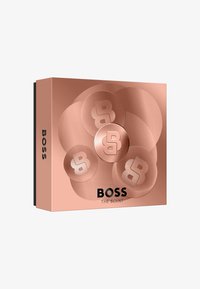 Caja de color oro rosa con patrones circulares y logotipos 'B' en relieve. El texto dice "BOSS THE SCENT" en letras negras en negrita en la parte frontal.