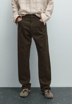 Braune Baumwolle-Twill-Hosen mit geradem Bein, vorderen Taschen und Knopfverschluss, kombiniert mit grauen Schuhen und einem beigefarbenen karierten Hemd.