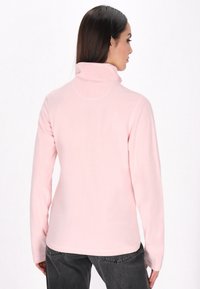 Pullover in fleece rosa chiaro con colletto alto e maniche lunghe. Texture morbida, design semplice e finitura liscia. La vista posteriore mostra le cuciture delle spalle.