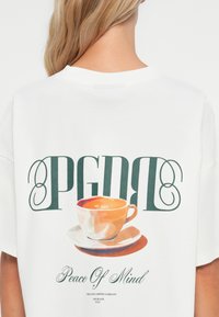 Tricou alb cu un design grafic ce include textul "PGDB" și o cană de cafea stilizată. Material neted, cu mâneci scurte și gât rotund.