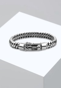 Silvermetallarmband med en vriden kedjedesign, med lås och en liten logodetalj. Mjuk, glänsande yta.