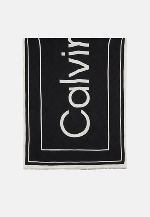 Czarny prostokątny szalik z białymi brzegami i częściowym dużym białym tekstem, czytanym pionowo jako "Calvin".