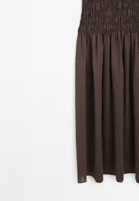 Bruine gestreepte rok met een smocked tailleband en gathered stof tegen een witte achtergrond.