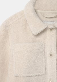 Cream-colored fleece jacket featuring a textured surface, a shirt collar, a button closure, and a patch pocket on the left side.
