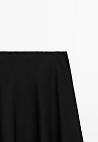 Sort A-line nederdel med en tætsiddende talje mod en ensfarvet hvid baggrund.