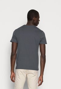 Graues Baumwoll-T-Shirt mit kurzen Ärmeln, rundem Halsausschnitt und lockerer Passform. Die Rückseite ist schlicht und hat keine sichtbaren Muster oder Logos.
