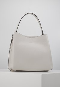 Grand sac à main blanc texturé au design minimaliste, avec une seule poignée ronde et des accents noirs subtils sur les bords.