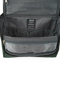 Interior de bolsa verde con un bolsillo de malla, múltiples compartimentos y un estuche transparente con cremallera. Forro con patrón y etiquetas visibles.