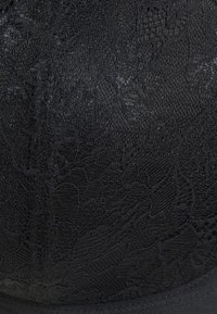 Tessuto in pizzo nero con motivo floreale, caratterizzato da una texture liscia e una forma strutturata. I bordi sono rifiniti con un bordo nero solido.