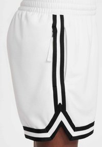 Λευκά αθλητικά σορτς με μαύρες κάθετες ρίγες και άκρη σε σχήμα γωνιανού βέλους, με ελαστική μέση και πλαϊνή τσέπη.