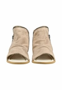 Beżowe perforowane zamszowe botki na otwarty palec z bocznymi suwakami i płaskimi jasnobrązowymi podeszwami, widziane z przodu na białym tle.