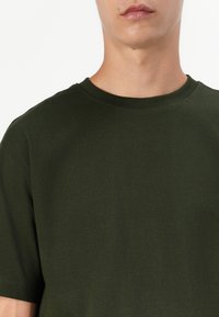 Olive green short-sleeve t-shirt made of soft cotton; features a classic crew neckline and plain, smooth texture with no visible patterns.